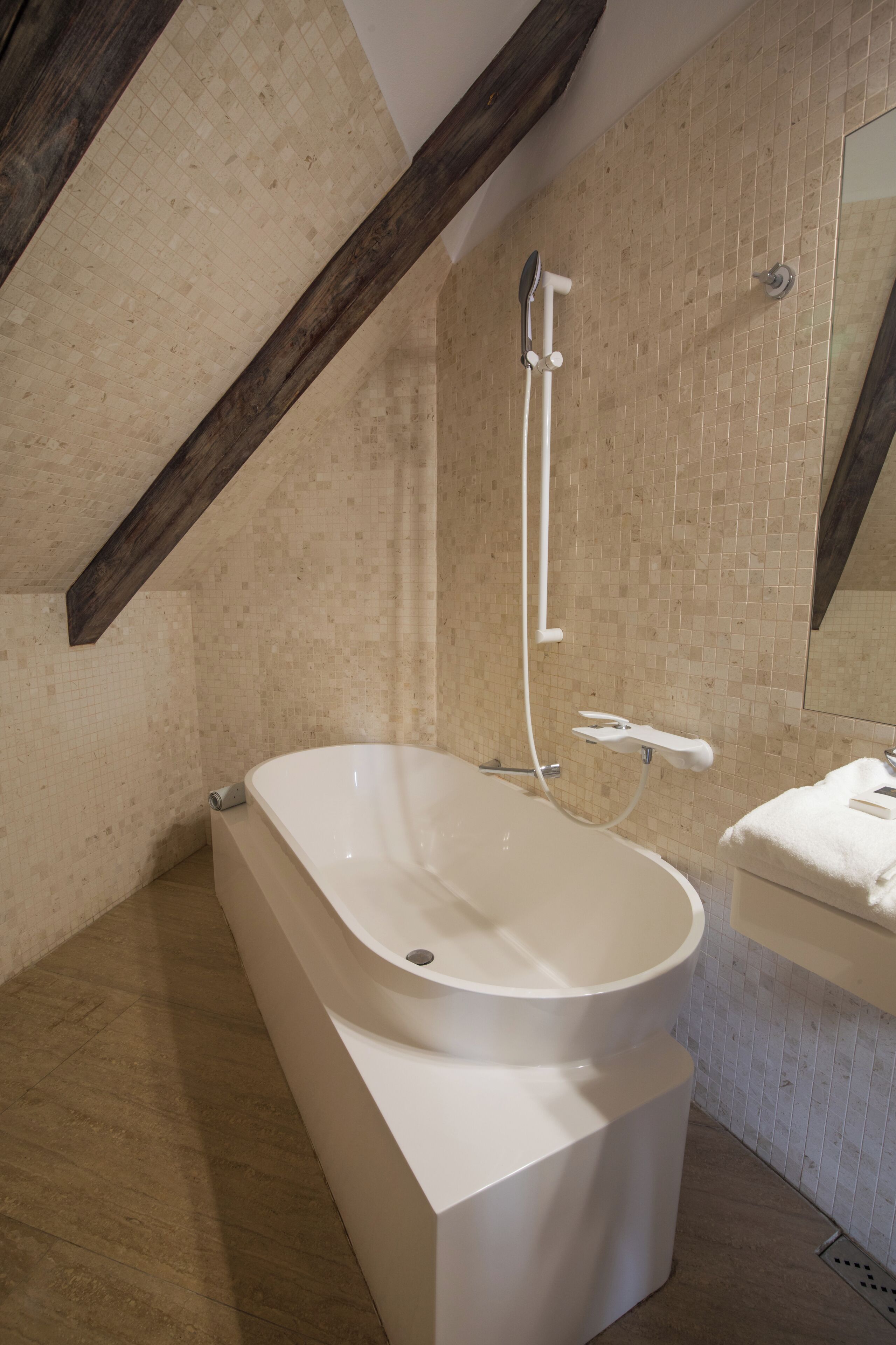 A modern bathroom with a freestanding bathtub, a showerhead, and a mirror above the sink.