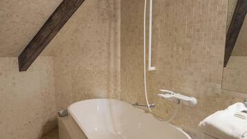 A modern bathroom with a freestanding bathtub, a showerhead, and a mirror above the sink.