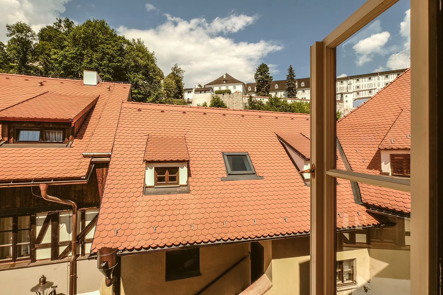 A traditional European building with red-tiled roofs, dormer windows, and a visible chimney.