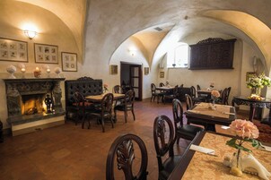 Un comedor con chimenea, mesas, sillas y una araña.