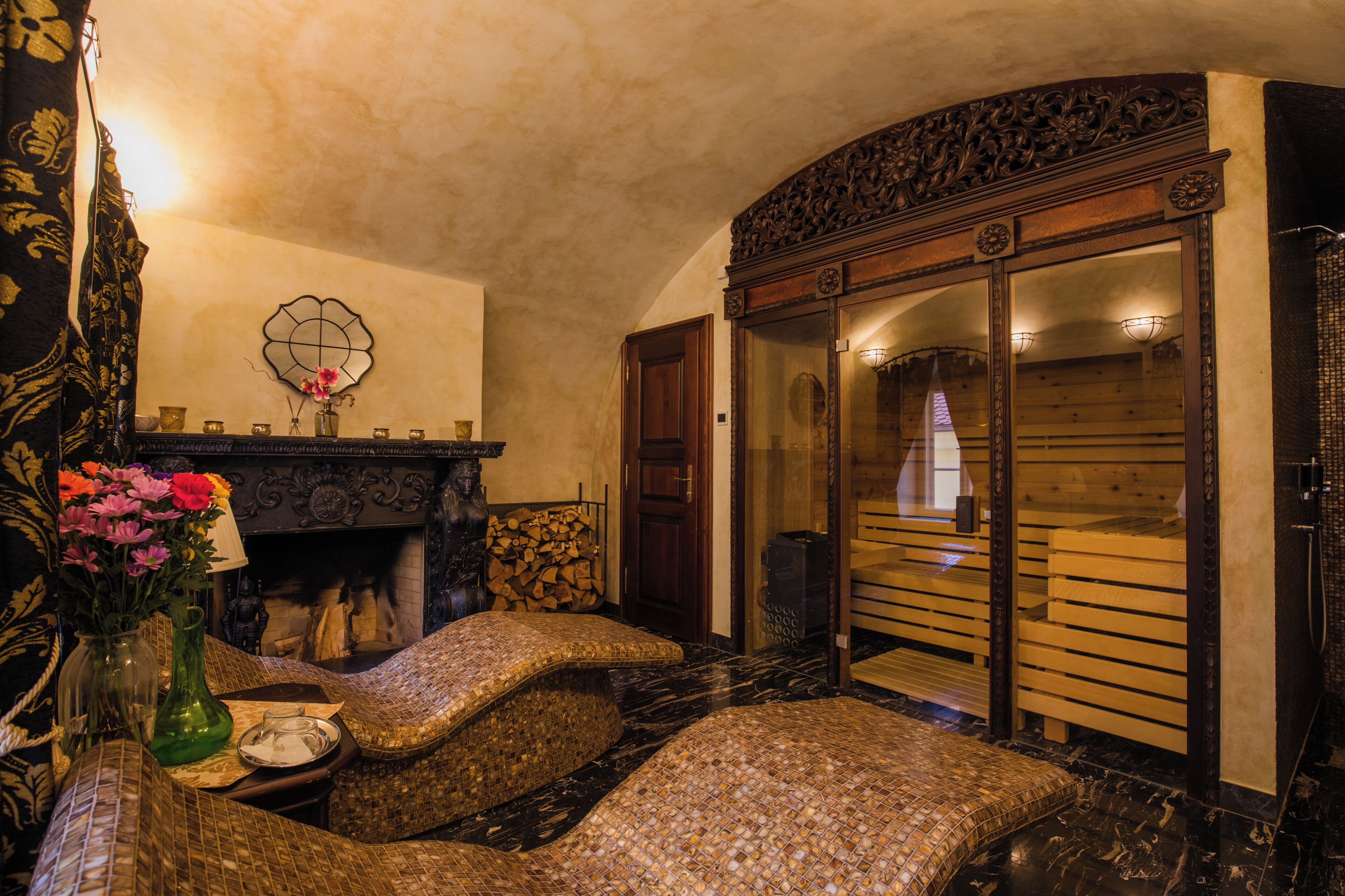 Una habitación con chimenea, espejo, banco de madera y puerta que da a una sauna.
