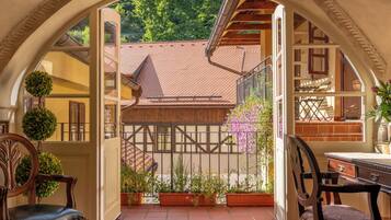 An arched entrance to a courtyard with a tiled floor, wooden furniture, and potted plants.