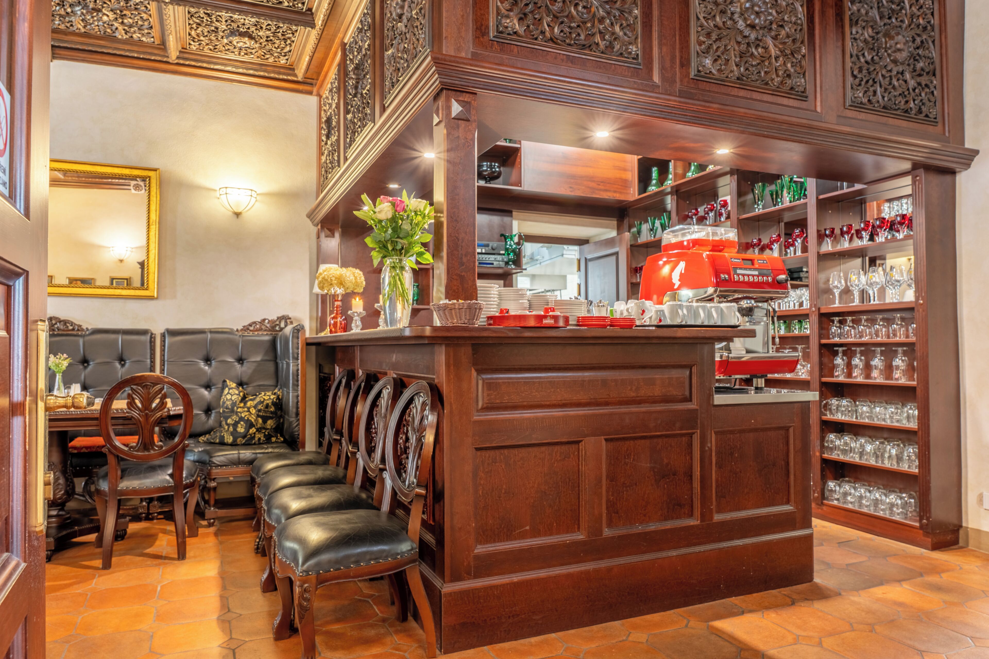 A bar area with a wooden counter, leather seating, and a wine rack.