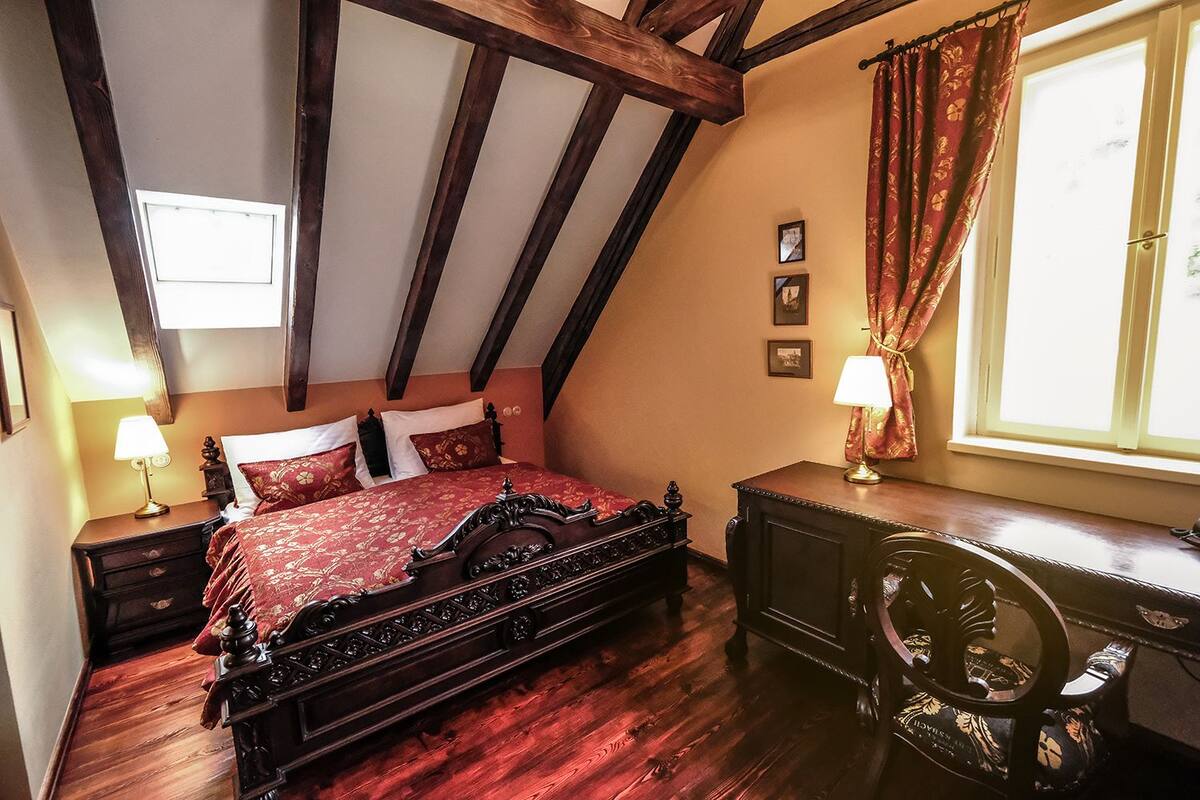 A bedroom with a wooden bed, a nightstand, a dresser, and a window with curtains.