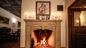 Una chimenea encendida, rodeada de cuadros enmarcados y velas sobre una repisa.