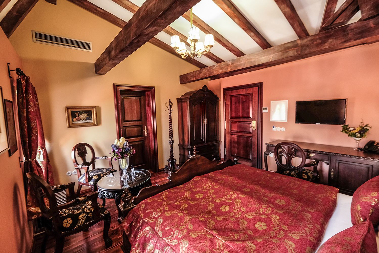 Un dormitorio con una cama grande, muebles de madera, una araña y un televisor.