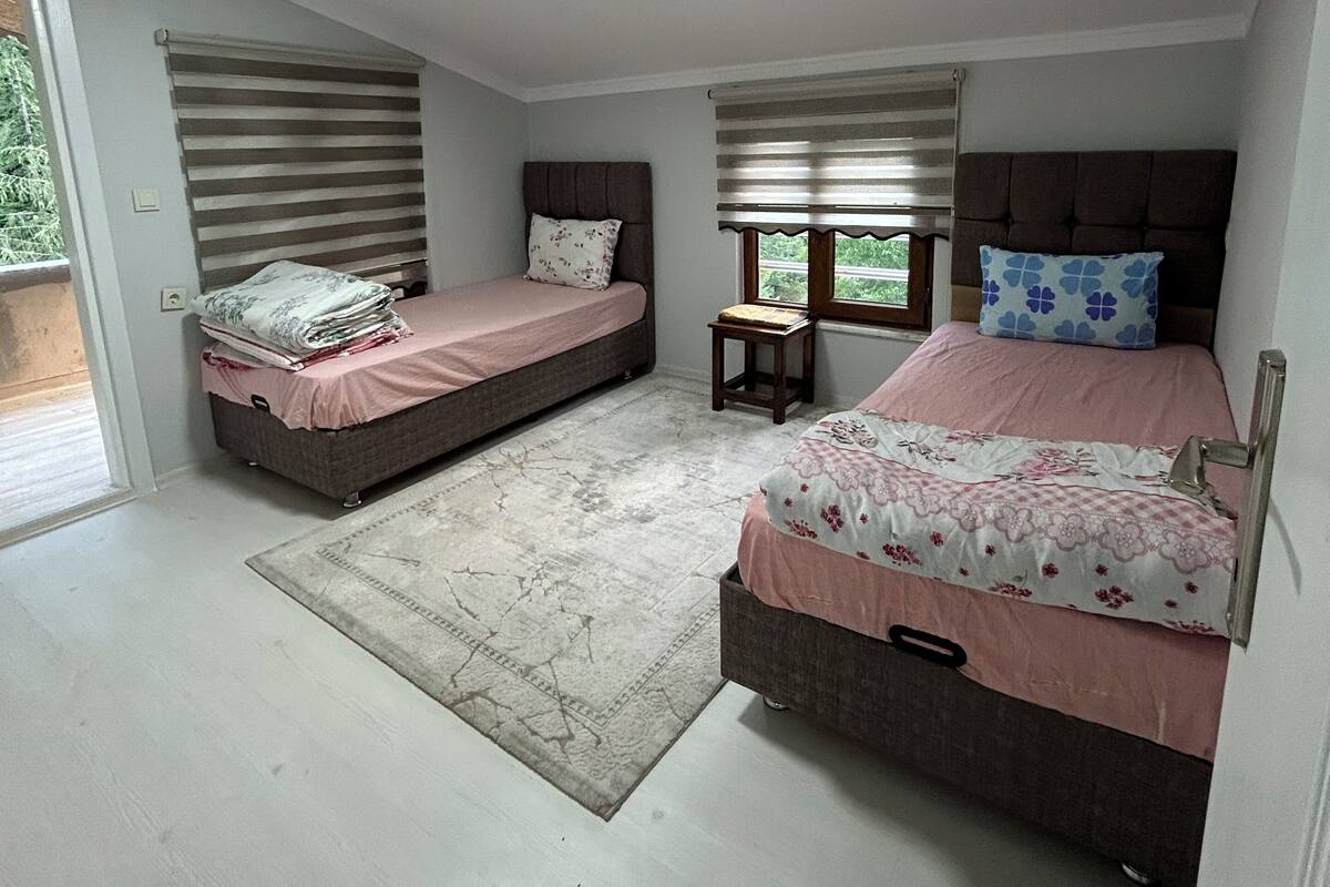 A bedroom with two beds, a small table, and a window.