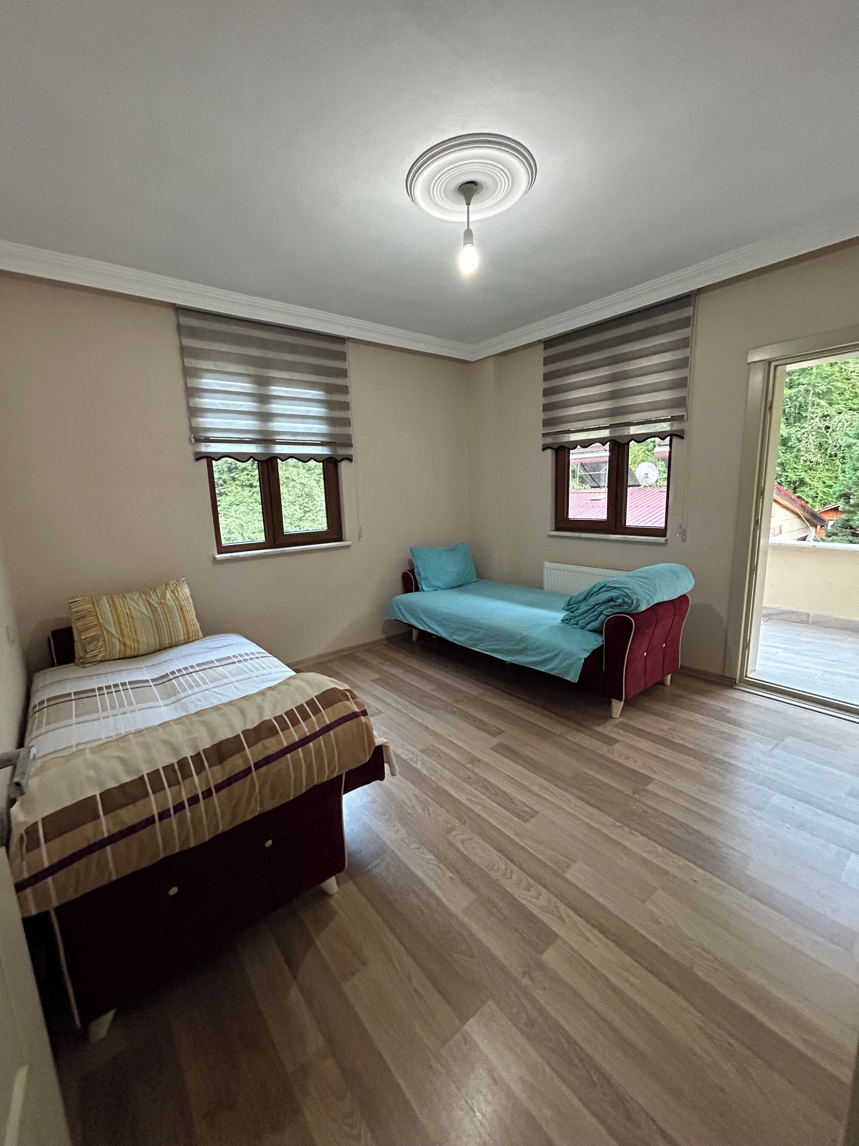 Un dormitorio con dos camas, ventilador de techo y ventanas con persianas.