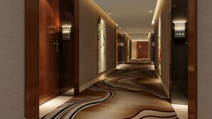A modern hotel hallway with wood paneling, a patterned carpet, and a digital elevator display. - VANHONG Hotel (Guangzhou)