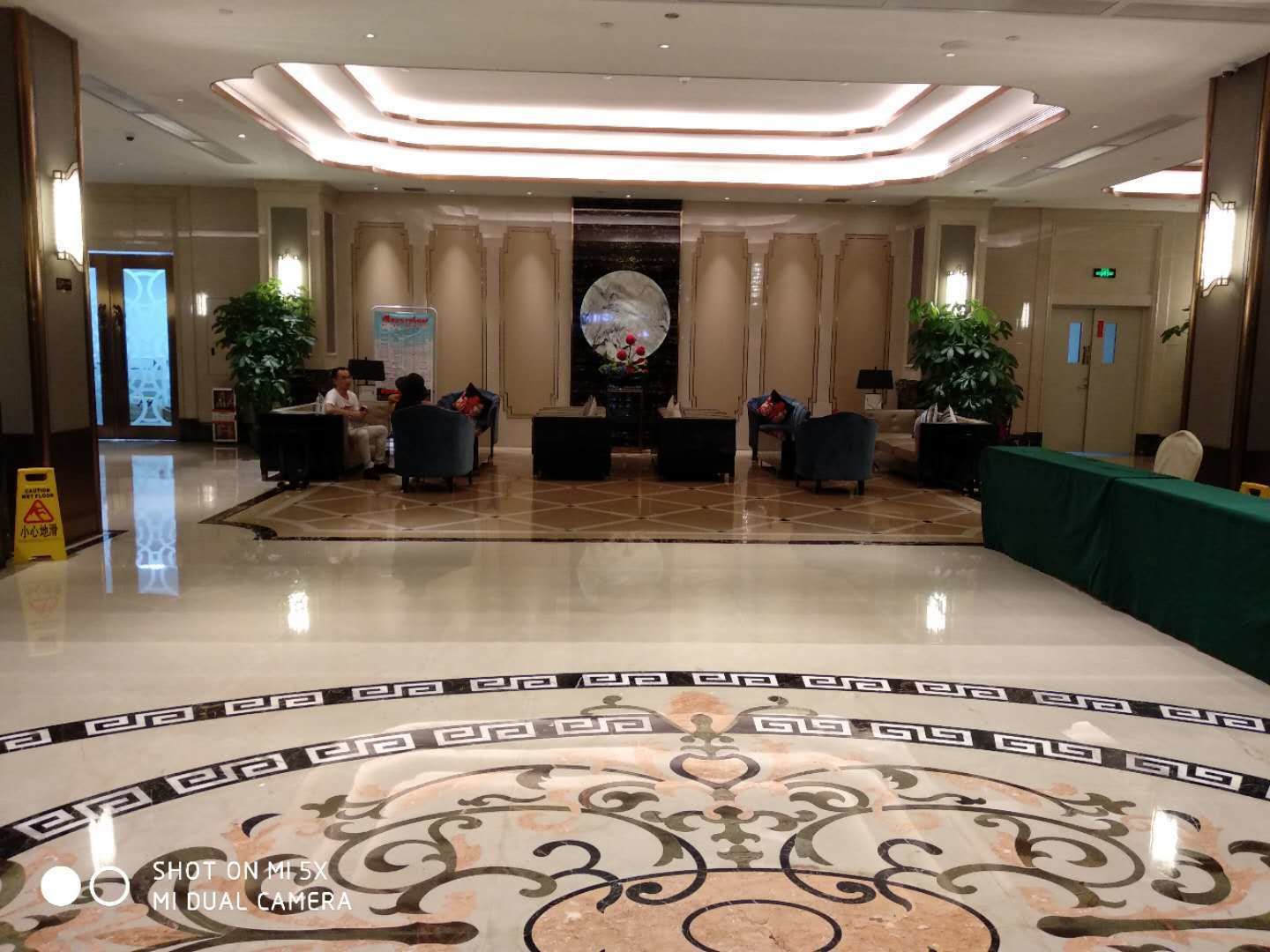 A spacious lobby with a polished marble floor, a reception desk, and seating areas.