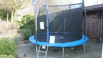 Enjoy outdoor fun with a trampoline set up on a paved surface surrounded by a safety fence.