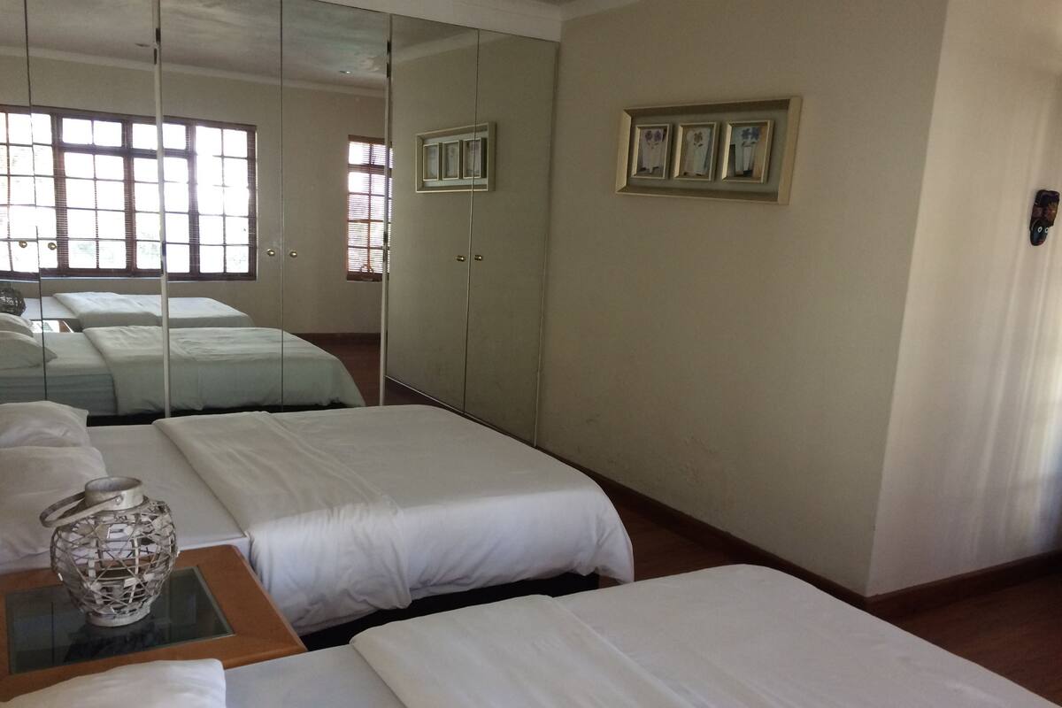 Habitación de hotel con dos camas, un espejo grande y una mesita con un objeto decorativo.