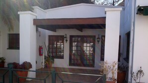 Un bâtiment blanc doté d’une entr ée abritée, de plantes en pot et d’un extincteur.