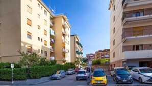Une rue étroite bordée d’immeubles résidentiels à plusieurs étages, de voitures garées et d’un panneau indiquant qu’il est interdit de se garer.