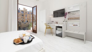 Une chambre d’hôtel équipée d’un lit, d’un bureau, d’une chaise, d’une télévision et d’une fenêtre donnant sur des immeubles.