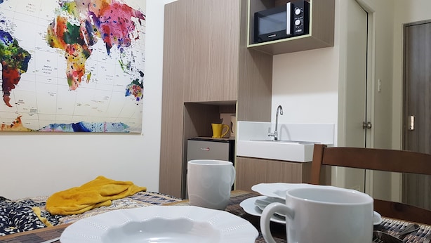 A compact kitchen with a microwave, sink, and a colorful world map on the wall. - Aorta Your Home in The Heart of EDSA (Mandaluyong)