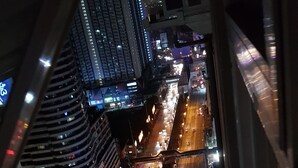 A nighttime cityscape with multiple lanes of traffic, illuminated buildings, and a pedestrian overpass. - Aorta Your Home in The Heart of EDSA (Mandaluyong)