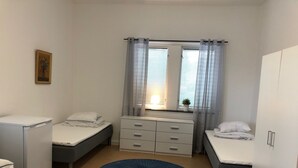 A small, clean room with two beds, a desk, a chair, and a window with curtains. - Hållsta Home Vandrarhem - Hostel (Husby-Rekarne)