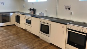 A modern kitchen with white appliances, a black countertop, and a wooden floor. - Hållsta Home Vandrarhem - Hostel (Husby-Rekarne)