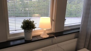 A window with blinds, a potted plant, and a table lamp. - Hållsta Home Vandrarhem - Hostel (Husby-Rekarne)