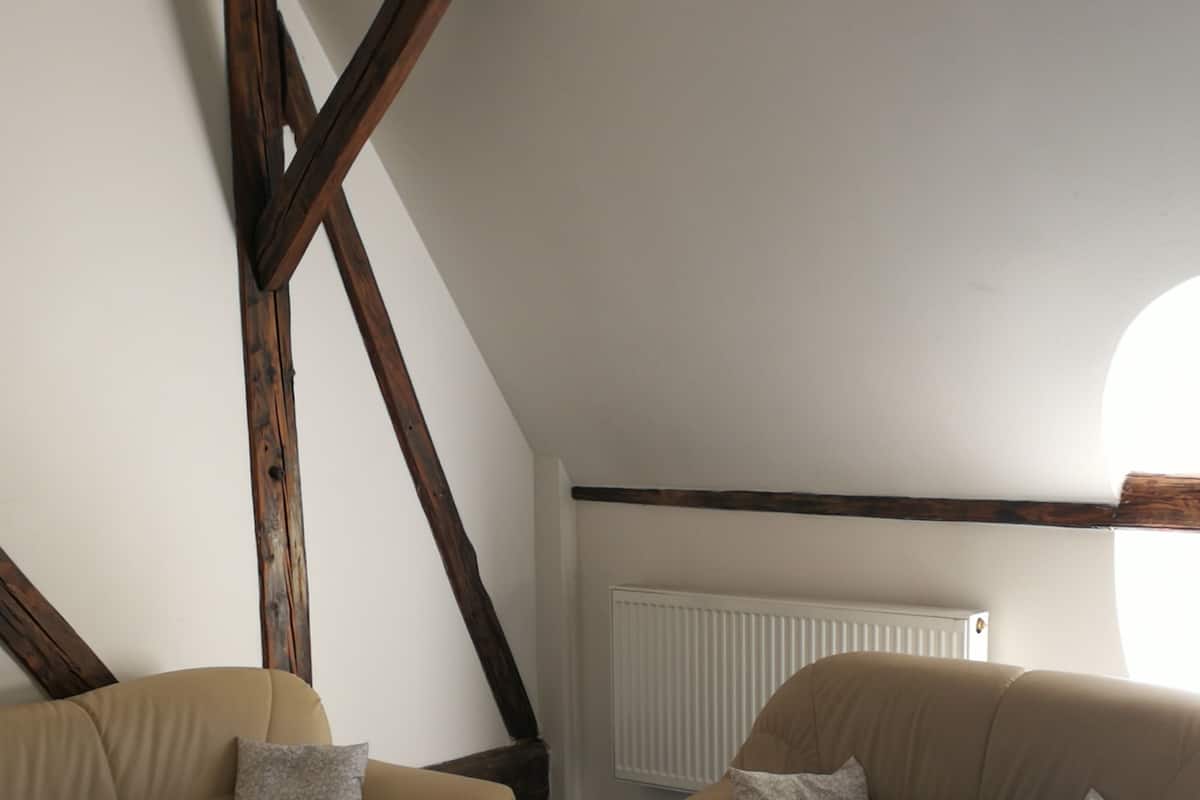 Una sala de estar acogedora con dos sofás, una mesa de centro y vigas de madera a la vista.