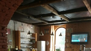 Una cocina acogedora con paredes de ladrillo, una isla central con utensilios de bar, luces colgantes y un televisor en la pared.