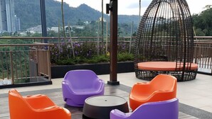 A rooftop terrace with colorful seating, a round table, and a birdcage. - Midhill by Cheng (Genting Highlands)