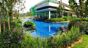 A modern building with a swimming pool surrounded by lush greenery and purple flowers. - Midhill by Cheng (Genting Highlands)