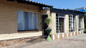 Um edifício com telhado de telhas, uma janela grande e um vaso de plantas.