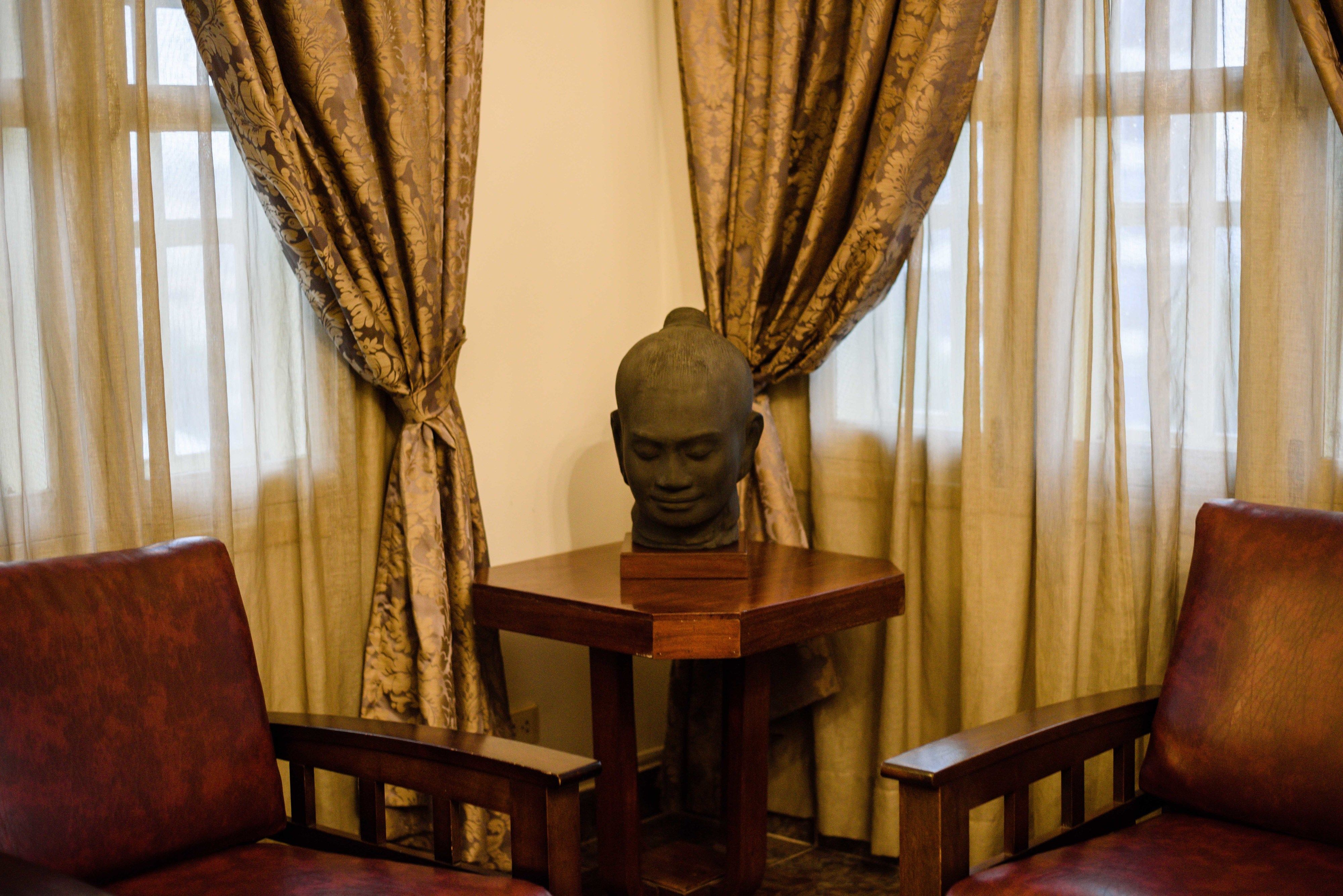 A room with a wooden table, two chairs, and a Buddha statue.