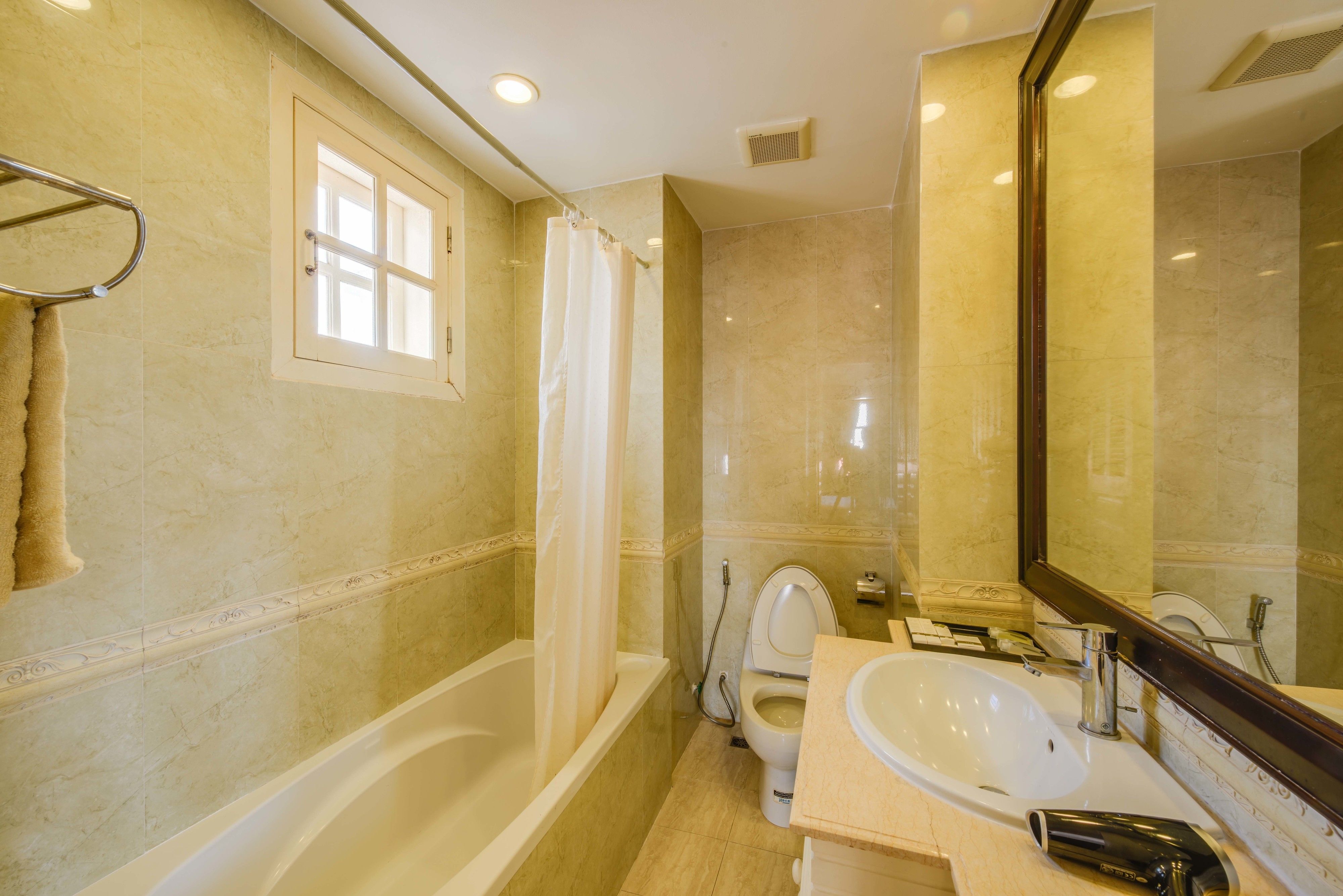 A bathroom with a bathtub, toilet, sink, and a large mirror.