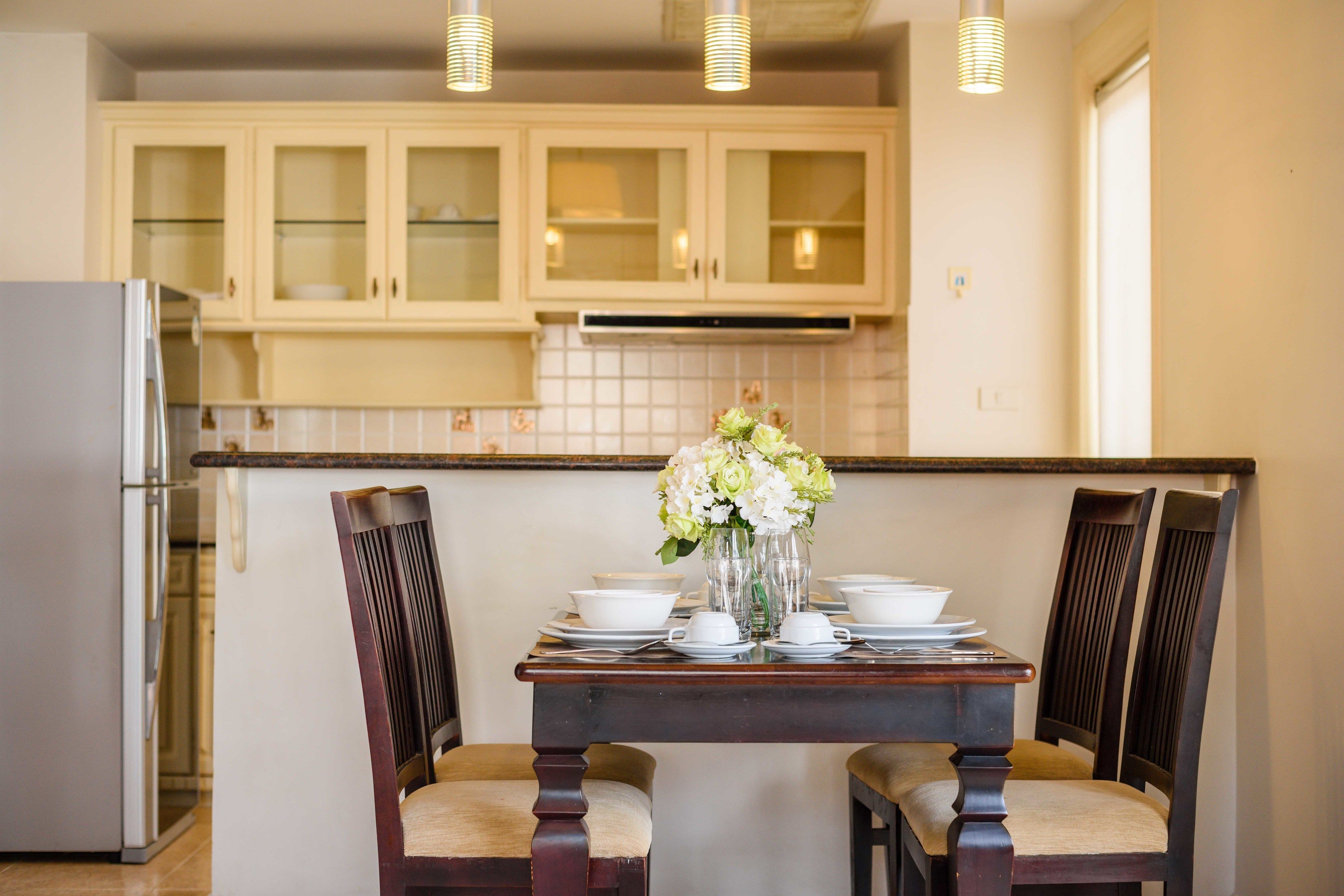 A kitchen with wooden cabinets, a dining table set with white dishes, and a vase with flowers.
