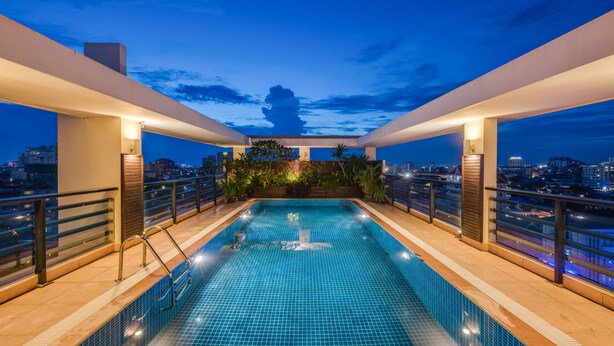 Una piscina en la azotea con vistas a la ciudad al anochecer.