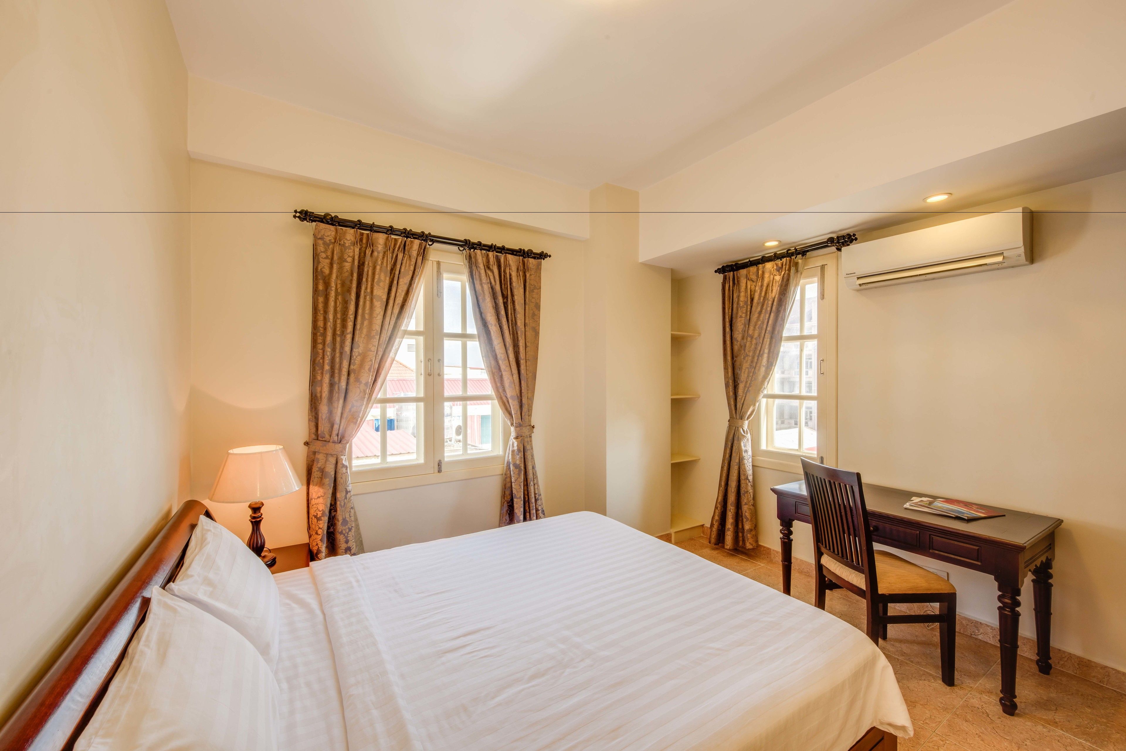Une chambre d’hôtel équipée d’un lit, d’un bureau, d’une chaise, d’une lampe et d’un appareil de climatisation.
