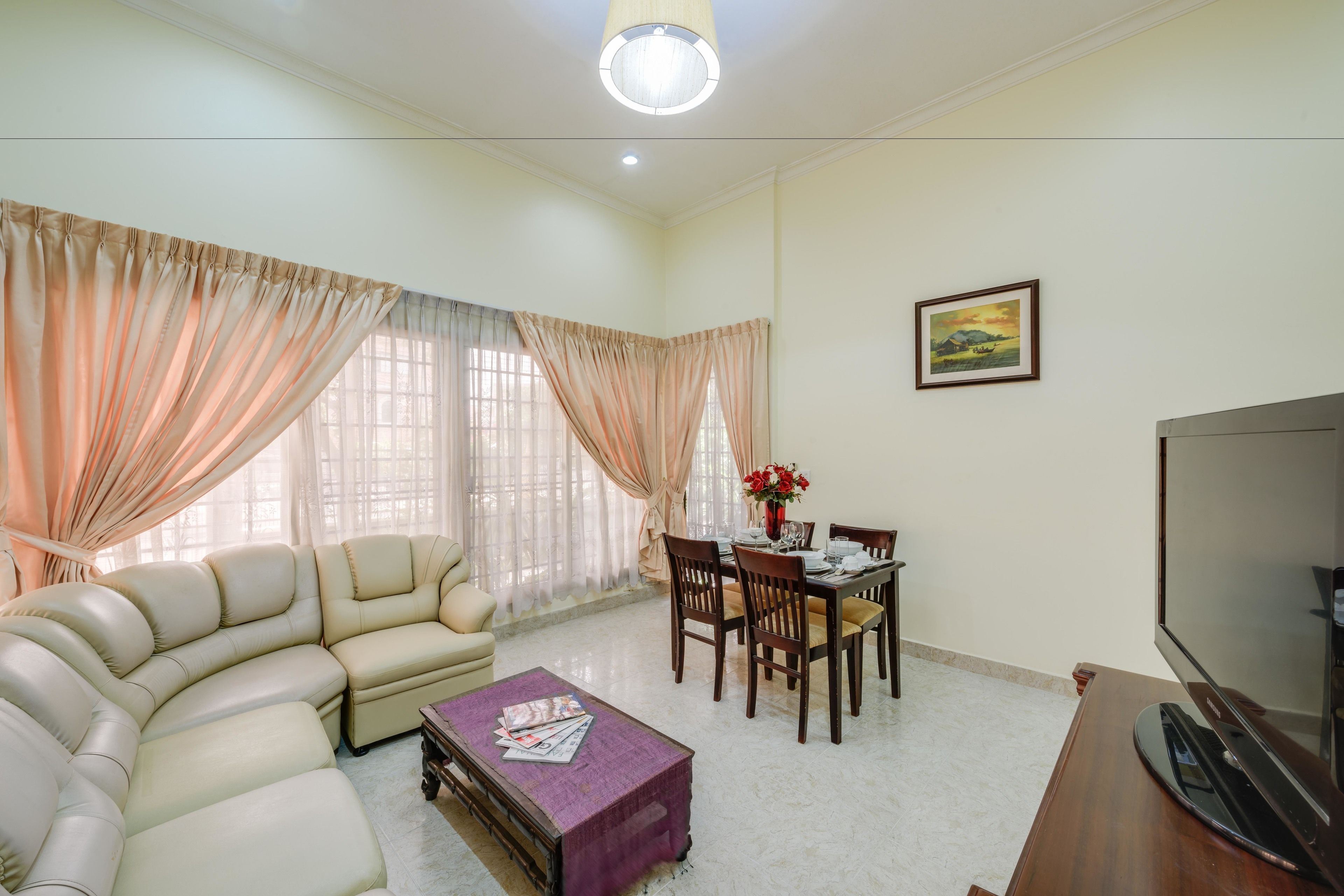 A living room with a sofa, dining table, chairs, a coffee table, and a TV.