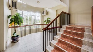 Un espacio interior amplio con una escalera curva, una planta en maceta y un equipo de aire acondicionado.