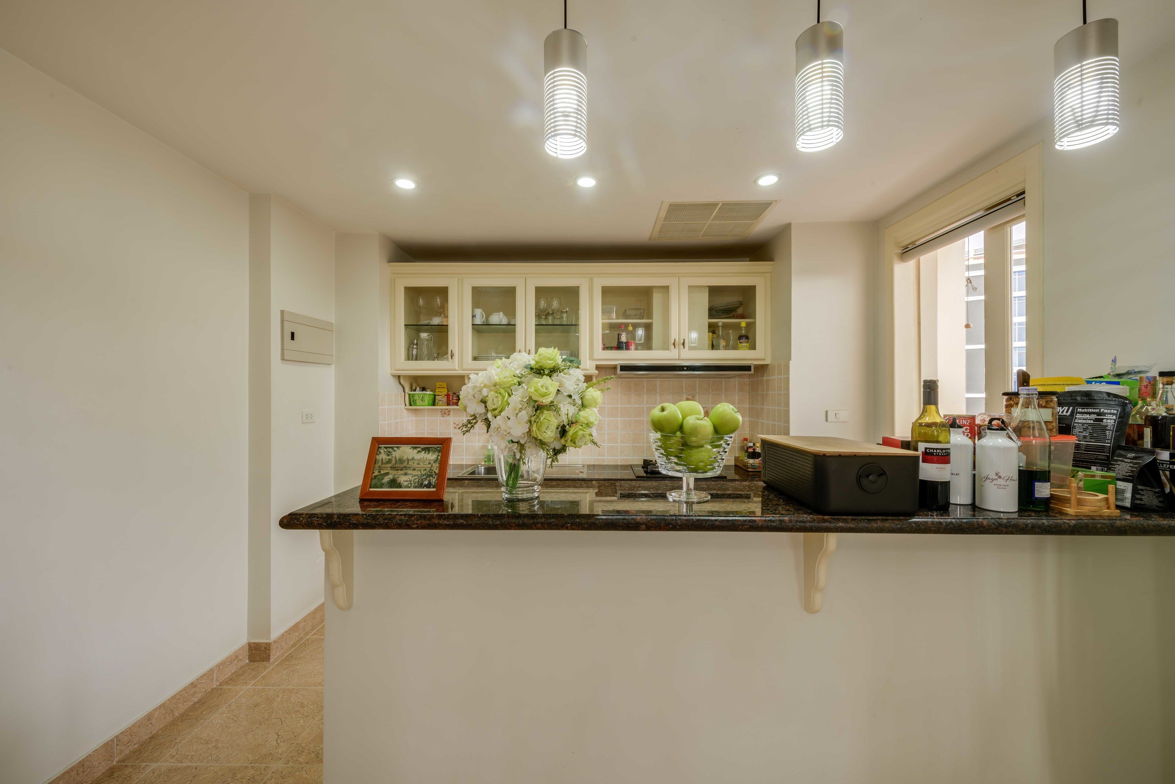 A kitchen with a marble countertop, a vase of flowers, and various kitchen appliances.