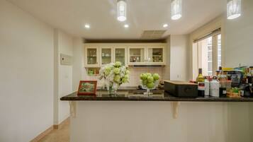 A kitchen with a marble countertop, a vase of flowers, and various kitchen appliances.