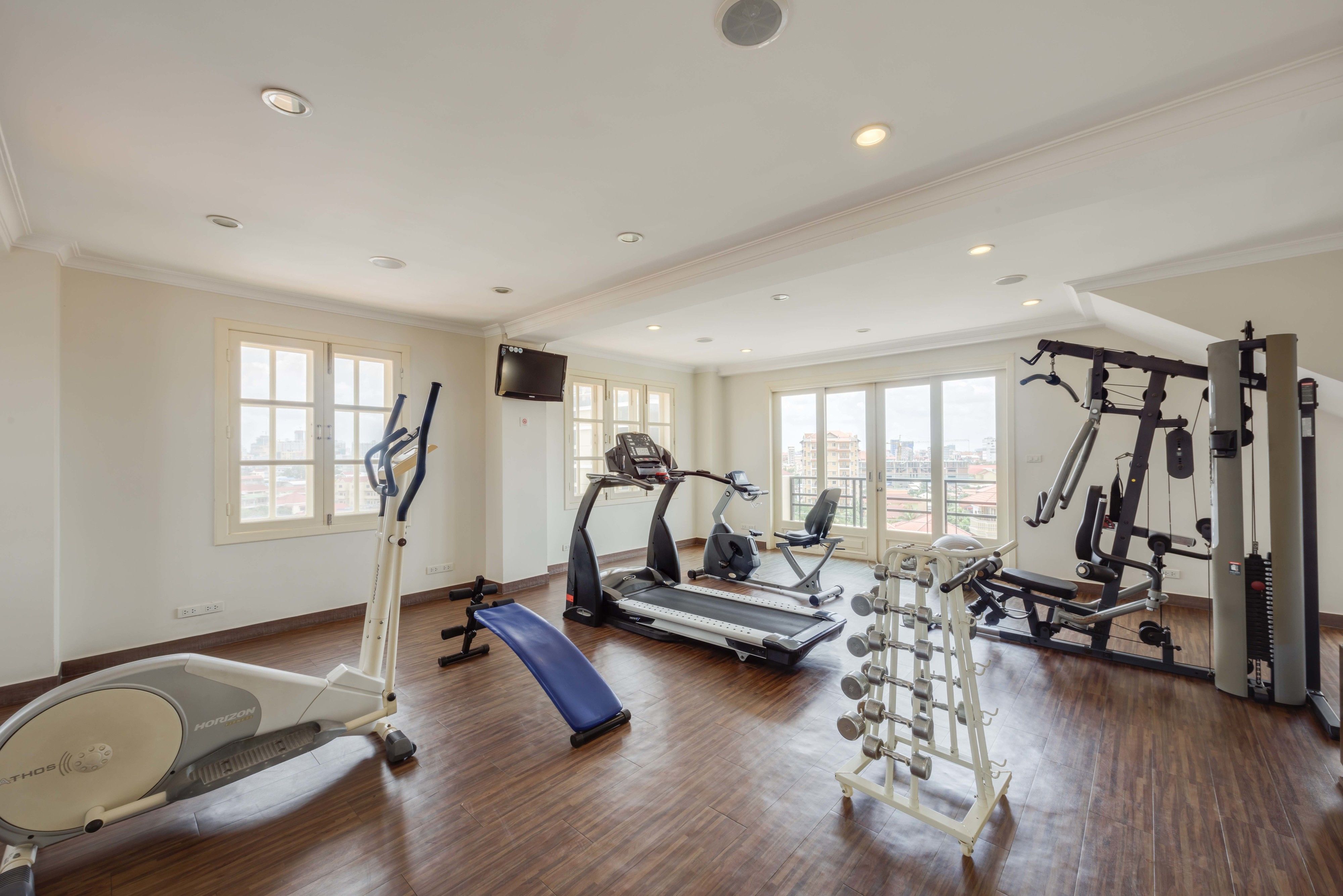Ett rymligt gym med löpband, crosstrainers, en bänk och utrustning för styrketräning.