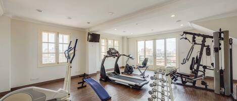 Ett rymligt gym med löpband, crosstrainers, en bänk och utrustning för styrketräning.