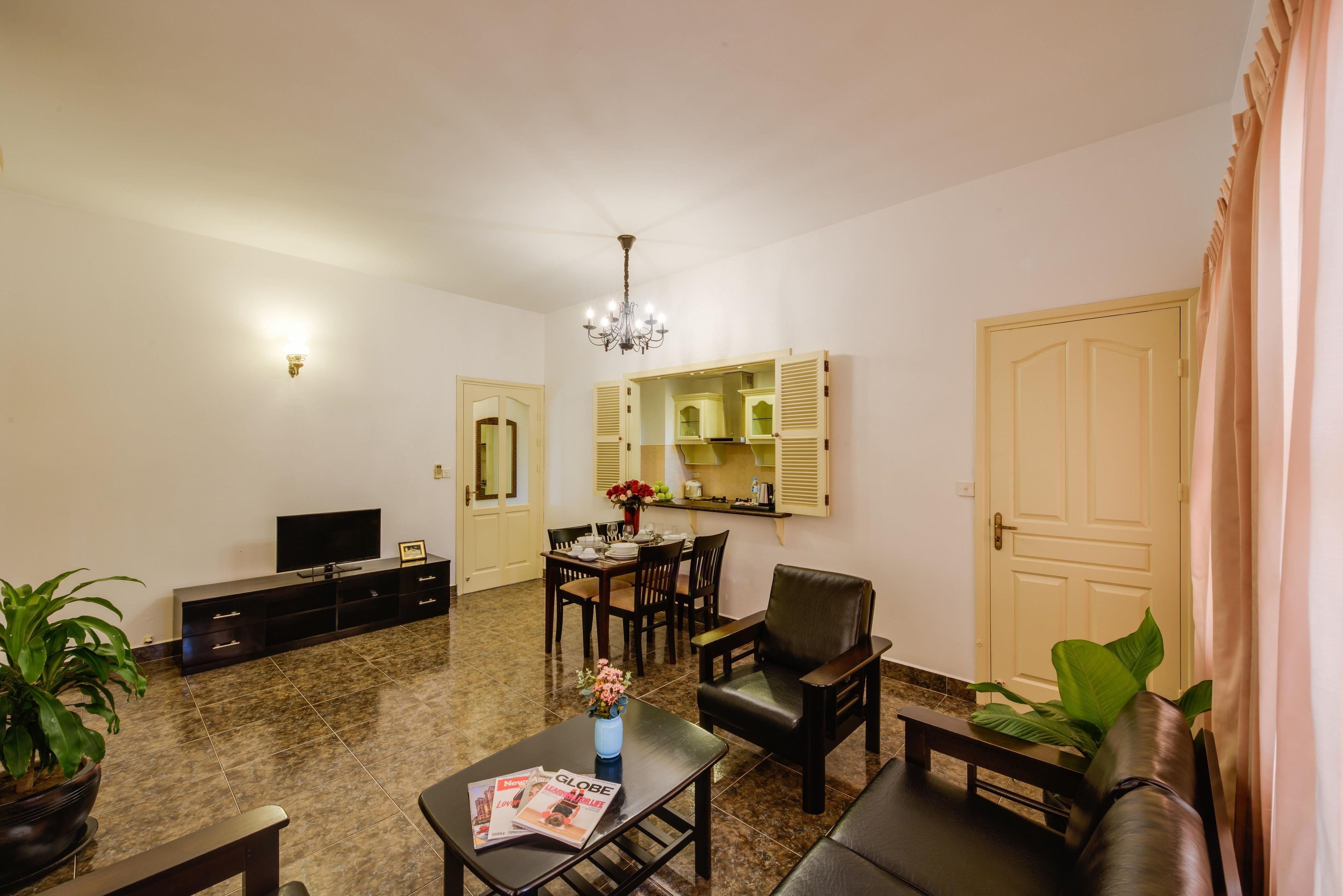 A living room with a TV, sofa, coffee table, and dining area.