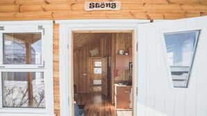 A wooden cabin interior with a visible kitchen area, a dining table, and a sign reading "Stöng". - Lindarbrekka (Djupivogur)