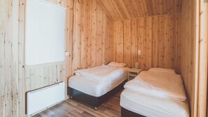 A room with two beds, wooden walls, a whiteboard, and a radiator. - Lindarbrekka (Djupivogur)