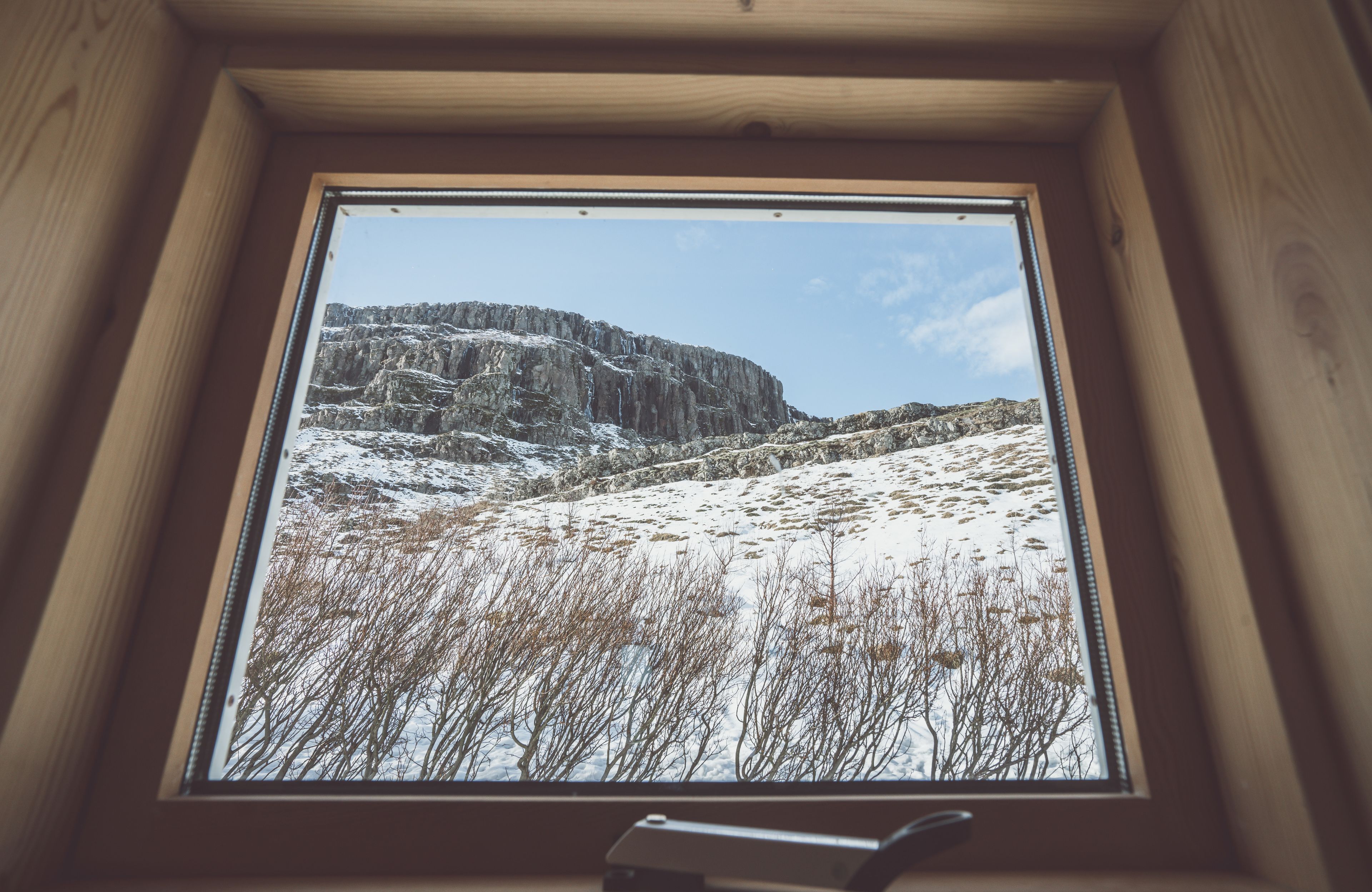 A window with a view of a snowy landscape and rocky cliffs.