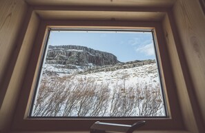 A window with a view of a snowy landscape and rocky cliffs.