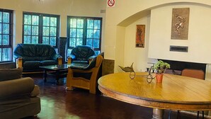 Une pièce spacieuse avec une table ronde en bois, des canapés en cuir et un lustre.