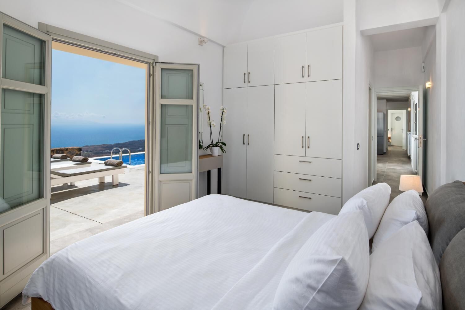 A bedroom with a bed, a wardrobe, and a view of the sea.