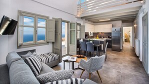 Un salon moderne comprenant un canapé, des coussins à motifs, une table à manger avec des chaises et un coin cuisine avec un réfrigérateur et une table à manger.