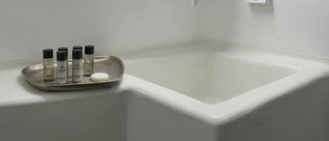 Un baño con un espejo redondo, un lavamanos y una bandeja con artículos de aseo.