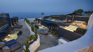 Un espace piscine aménagé sur le toit, avec des chaises longues, un jacuzzi et une vue sur l’océan.